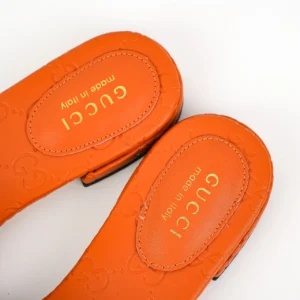 Gucci Double G women's slippers in orange sheepskin leather with embossed logo and "made in Italy" inscription, showcasing luxury design and brand authenticity.