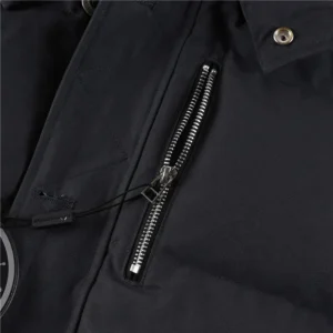 Close-up of Moose Knuckles Men's Original 3Q Shearling Trim Down Jacket featuring a zippered pocket and logo detail, highlighting high-quality materials and craftsmanship.