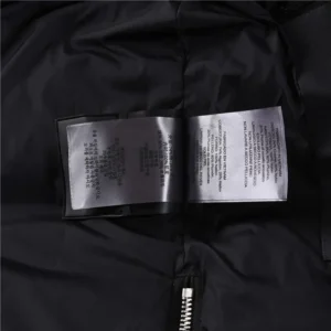 Interior label of Moose Knuckles Men's Original 3Q Shearling Trim Down Jacket, featuring care instructions and brand details on a black fabric background.