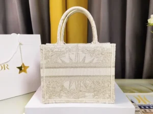 Dior Small Gold Dream Rêve d’Infini Pattern Tote handbag featuring intricate embroidery and Christian Dior logo, displayed on a white pedestal with a Dior gift box in the background.