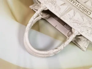 Dior Small Gold Dream Rêve d’Infini Pattern Tote featuring embroidered design and CHRISTIAN DIOR logo, displayed on a soft, neutral background.