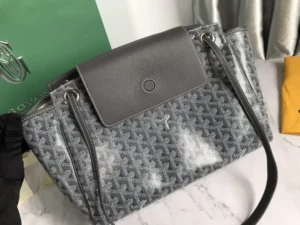Goyard Rouette bag featuring a gray patterned exterior, leather flap closure, and dual shoulder straps, displayed on a marble surface with contrasting background elements.