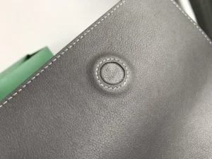 Close-up of the Goyard Rouette bag's textured gray leather featuring a circular embossed logo detail, highlighting its luxury craftsmanship and design quality.