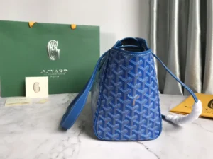 Goyard Rouette bag in blue, featuring signature pattern, adjustable strap, and luxury packaging on a marble surface.