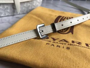 Goyard Single Mailman Bag strap on yellow storage pouch with logo, showcasing adjustable buckle and high-quality leather craftsmanship.