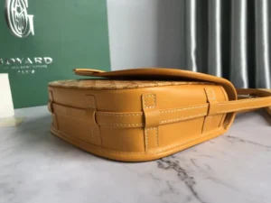 Goyard Belv é d è re Single Mailman Bag in yellow leather with woven detailing, showcasing the elegant design and craftsmanship, against a green Goyard backdrop.