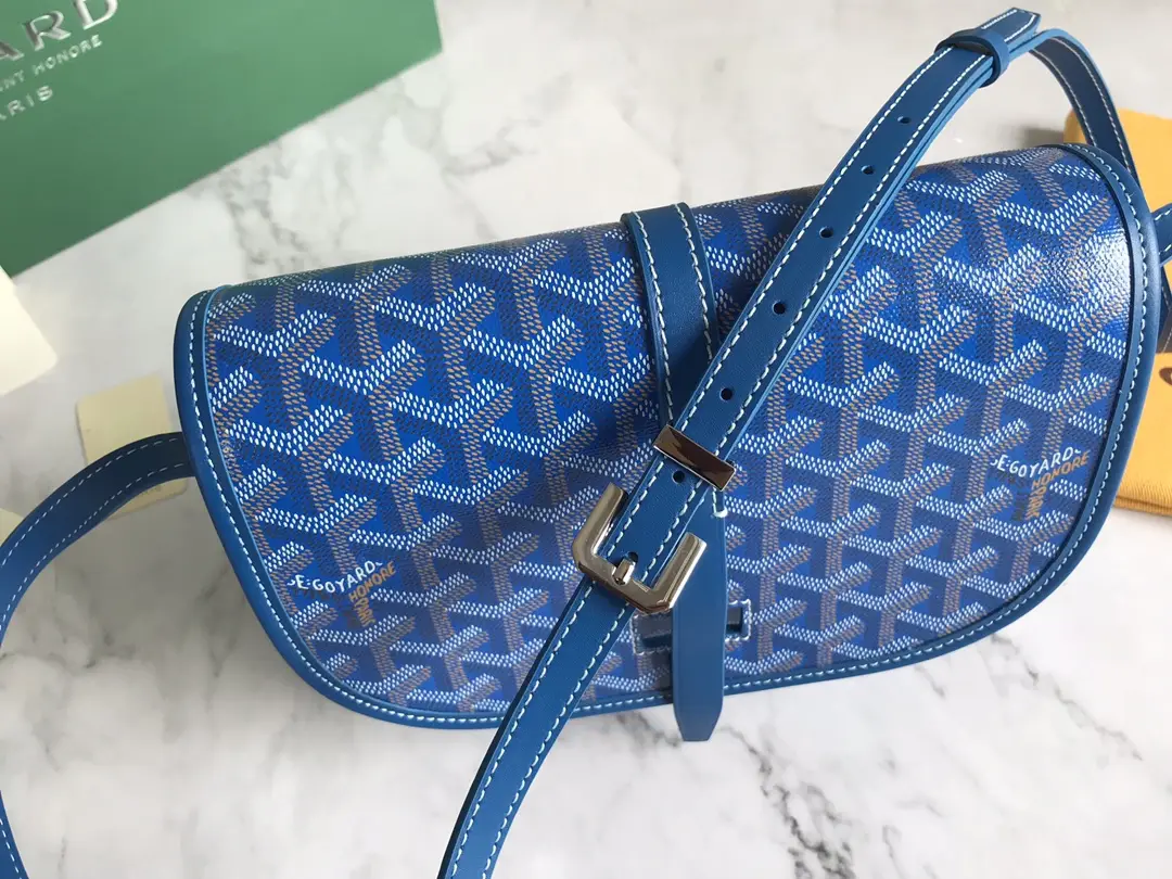 Goyard Belv é d è re Single Mailman Bag in blue with signature pattern, adjustable strap, and leather detailing on marble surface.
