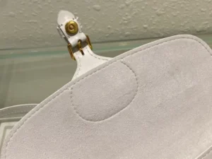 Close-up view of the interior of a Dior Bobby East-West Bag, showcasing soft white suede material and a gold clasp detail, emphasizing luxury and craftsmanship.