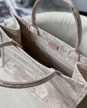 Dior Book Tote Bag in light pink, showcasing spacious interior and "CHRISTIAN DIOR" branding, emphasizing luxury and stylish design.