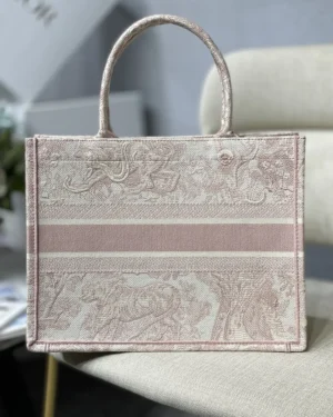 Dior Book Tote Bag in pink and beige, featuring intricate patterns and a structured design, displayed on a neutral background.