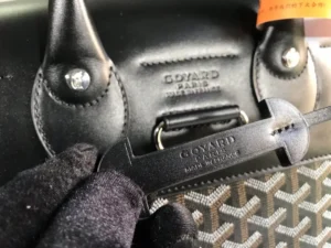 Goyard Alpin backpack detail showing leather handles, logo embossing, and craftsmanship elements.