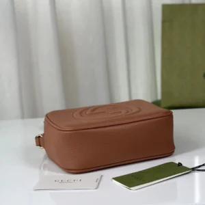 Gucci Apricot Leather Tote displayed on a white surface with tags and a green shopping bag in the background.