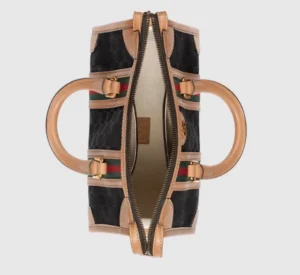 Gucci Exquisite Small Canvas Handbag featuring black GG canvas, brown leather rolled edges, gold adjustable accessories, and interior zipper pockets, showcasing luxury design elements and craftsmanship.