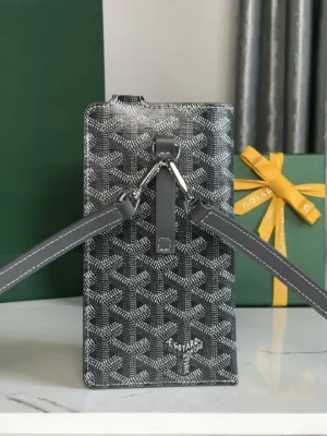 Goyard MontMartre GM bag in grey with signature pattern, featuring adjustable straps and a stylish design, set against a green background and gift box.