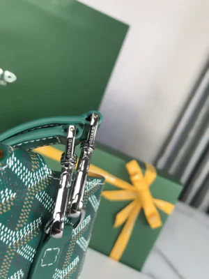 Goyard MontMartre GM Green bag featuring silver zippers, with a green gift box and yellow ribbon in the background, emphasizing stylish design and versatility for everyday use.