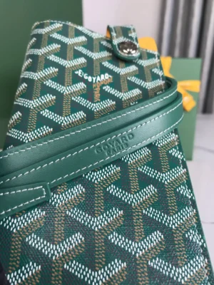 Goyard MontMartre GM Green wallet featuring signature pattern, stylish design, and adjustable strap, placed next to a gift box.