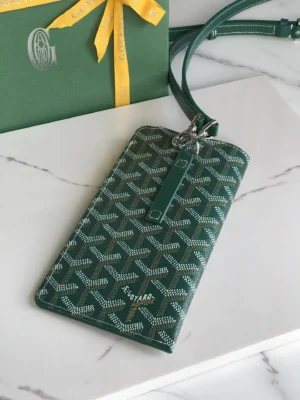 Goyard MontMartre GM Green wallet with signature pattern, stylish design, and adjustable strap, presented on a marble surface alongside a branded box and ribbon.