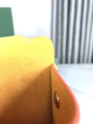 Interior view of Goyard MontMartre GM bag showcasing vibrant orange and yellow leather, emphasizing craftsmanship and design details.