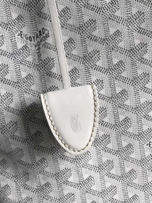 Goyard Tote Bag Commuter Series detail featuring white protective cover with embossed logo against patterned canvas background.