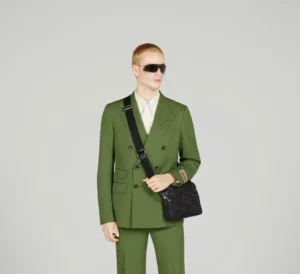 Model wearing a green suit and sunglasses, showcasing the Super Double G Postman Bag from Gucci's 2023 Spring/Summer collection.
