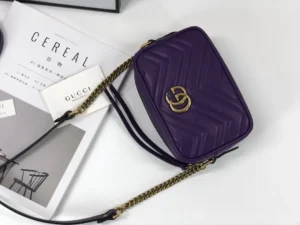 Gucci GG Marmont small shoulder bag in purple with interlocking Double G logo, featuring chevron quilted leather and chain strap, displayed on a white surface with branded tags.