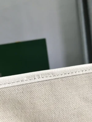 Hermes bag close-up showing white leather edge and canvas material with "Made in France" embossed text