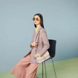 Model sitting on a chair wearing sunglasses and a stylish outfit, showcasing the Gucci Petite GG Series Small Shoulder Bag.