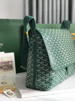 Goyard Citadin Mailman Bag in green featuring signature pattern, displayed on a table with nearby documents, emphasizing its stylish and functional design.
