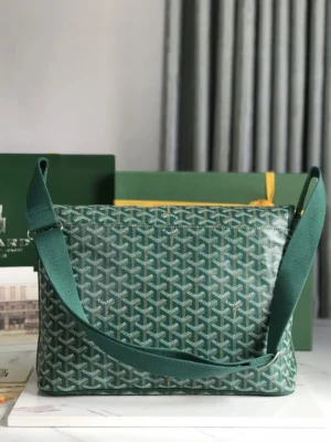 Goyard Citadin Mailman Bag in green, featuring a distinctive pattern, adjustable strap, and elegant design, positioned against a neutral backdrop with packaging elements.