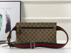 Brown Gucci leather handbag with signature logo pattern and green-red striped strap, displayed against a minimalist background.