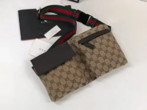 Brown leather handbag with Gucci logo, featuring a stylish design, dual compartments, and a green-red strap, showcased on a neutral background.