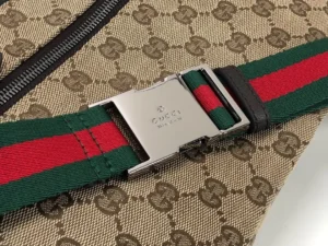 Close-up of Gucci handbag strap featuring iconic green and red stripes and logo buckle, showcasing designer quality and detail.