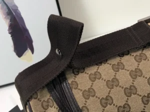 Close-up of Gucci Premium GG Canvas Leather Tote handle featuring brown fabric and logo pattern, emphasizing quality design and craftsmanship.