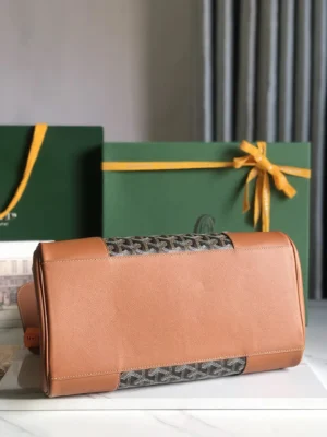 Goyard Saigon Tote bag in tan leather and signature canvas, displayed on a marble surface with green gift boxes in the background, highlighting its elegant design and luxury appeal.
