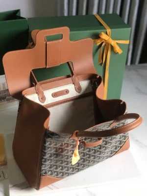 Goyard Saigon Tote bag with a brown leather exterior and open interior, showcasing its spacious design and elegant style, placed next to a green gift box with a yellow ribbon.