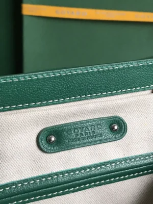 Goyard Saigon Tote interior detail showcasing green leather trim and brand tag on canvas background.