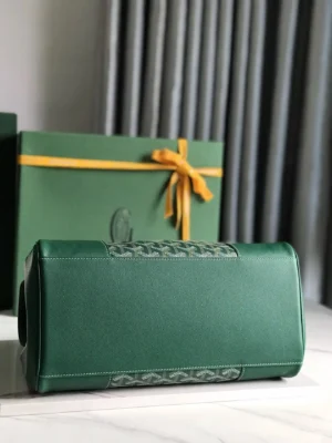 Goyard Saigon Tote bag in green leather, featuring a decorative woven pattern, displayed against a backdrop of a gift box with a yellow ribbon.