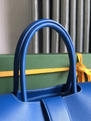 Goyard Saigon Tote bag in vibrant blue with elegant handles, displayed next to a green Goyard box, highlighting luxury craftsmanship and style.