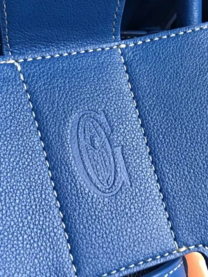 Goyard Saigon Tote bag detail featuring embossed G logo on blue textured leather, emphasizing luxury and craftsmanship.