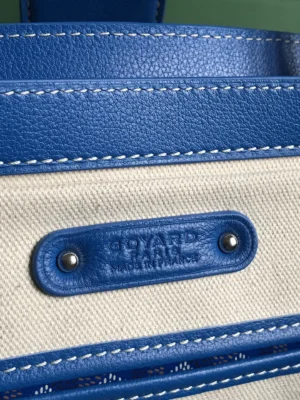 Goyard Saigon Tote bag detail featuring blue leather trim and logo tag on canvas.