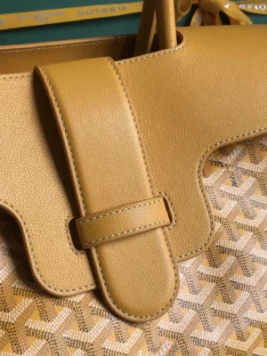 Goyard Saigon Tote bag detail featuring yellow leather strap and signature patterned fabric, highlighting luxury design and craftsmanship.