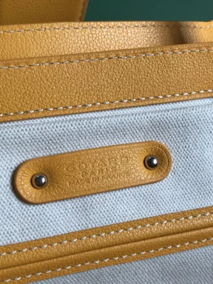Goyard Saigon Tote bag close-up, showcasing the textured leather and embossed logo tag, highlighting its luxury design and craftsmanship.