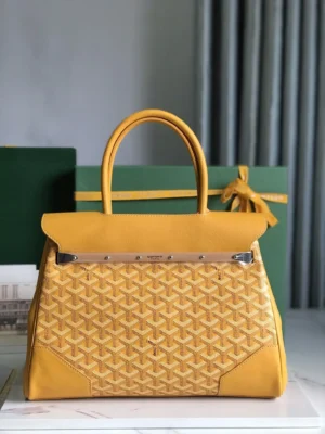 Goyard Saigon Tote bag in vibrant yellow, showcasing woven texture and elegant design, placed on a surface with green gift boxes in the background.