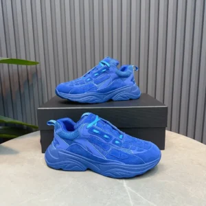 AMIRI Trainer sneakers in vibrant blue color, displayed on a black box with a textured background, showcasing luxury footwear design.