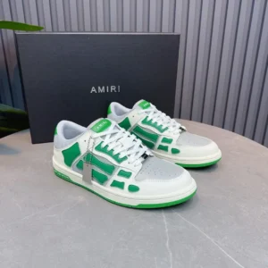 AMIRI BONE SHOE in green and white colorway displayed on a gray surface with branded box in the background, highlighting luxury sneaker design.