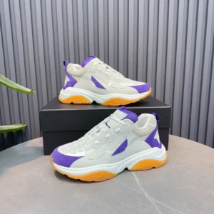 AMIRI Trainer replica sneakers in grey, purple, and orange, displayed on a black box against a textured background, showcasing luxury footwear design.