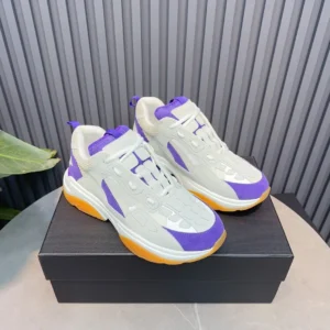 AMIRI Trainer replica sneaker in white and purple, displayed on a black box, highlighting luxury design and vibrant color accents.