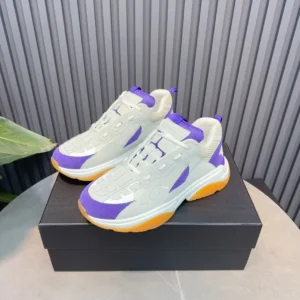 AMIRI Trainer replica sneakers in white, purple, and orange colorway displayed on a black box, highlighting luxury design and style.
