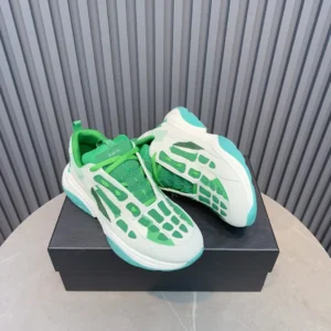 Amiri Trainer sneakers in green and white design displayed on a black box, showcasing unique mesh detailing and modern aesthetic.