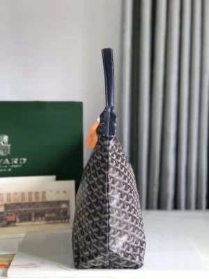 Goyard Hobo Boh è Me Stray Bag featuring a distinctive woven pattern, side view showcasing the bag's sleek design and comfortable shoulder strap, with a green Goyard box in the background.